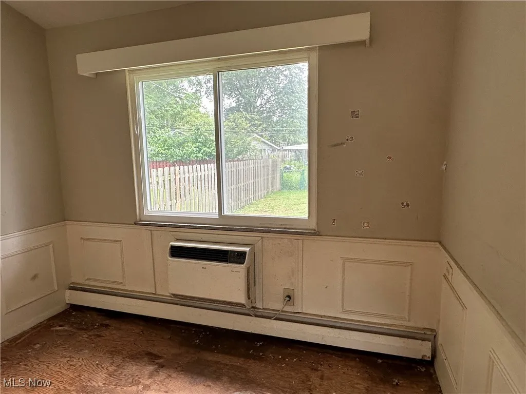 Unfurnished room featuring a decorative wall, a wainscoted wall, and a baseboard radiator