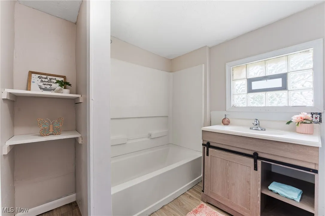 Bathroom with wood finished floors, vanity, and washtub / shower combination