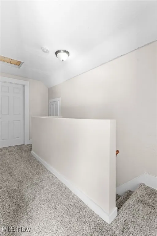 Hallway featuring carpet floors and an upstairs landing