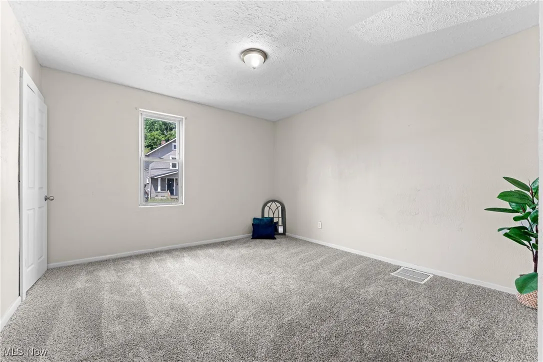 Carpeted spare room featuring baseboards and a textured ceiling