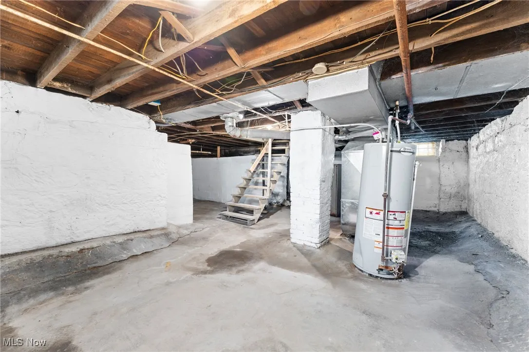 Unfinished below grade area featuring stairway and gas water heater