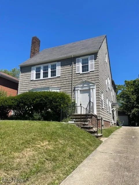 Colonial-style house with a front yard, a garage, and a chimney