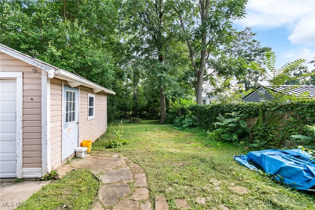 View of grassy yard with an outdoor structure and a garage