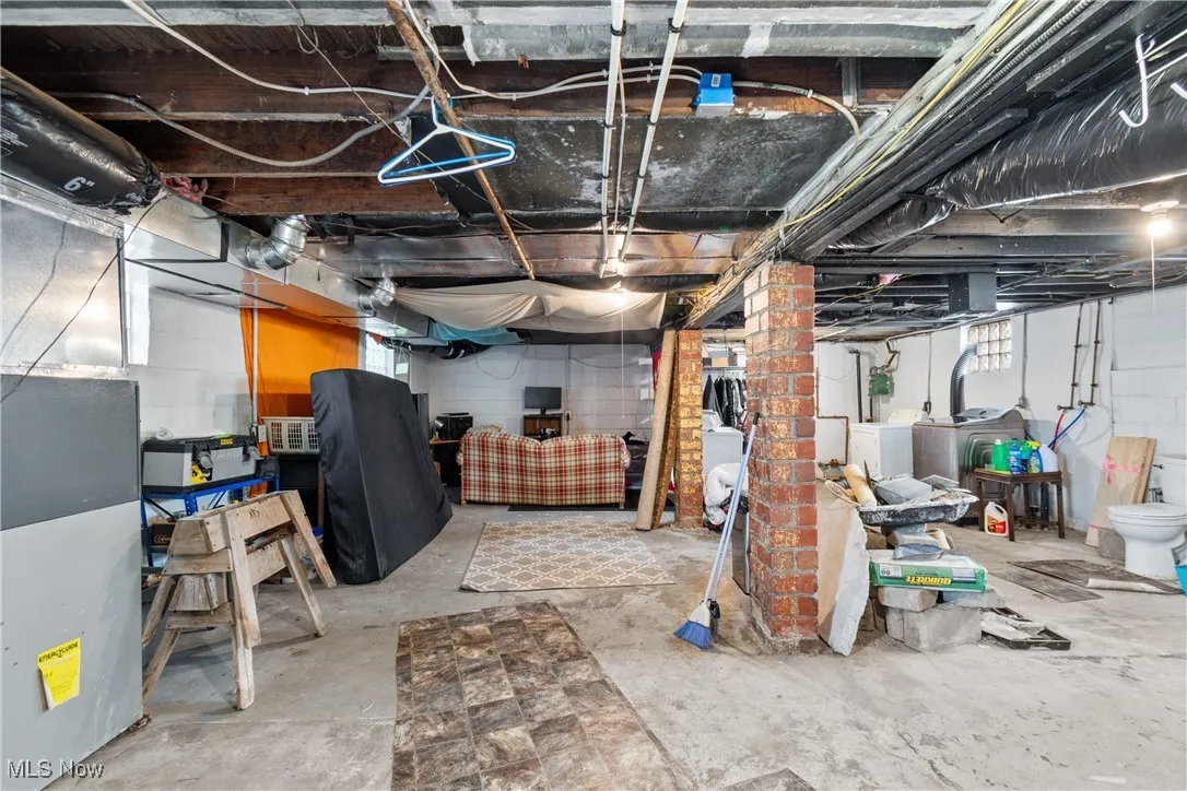 Below grade area featuring washer and dryer, heating unit, and healthy amount of natural light