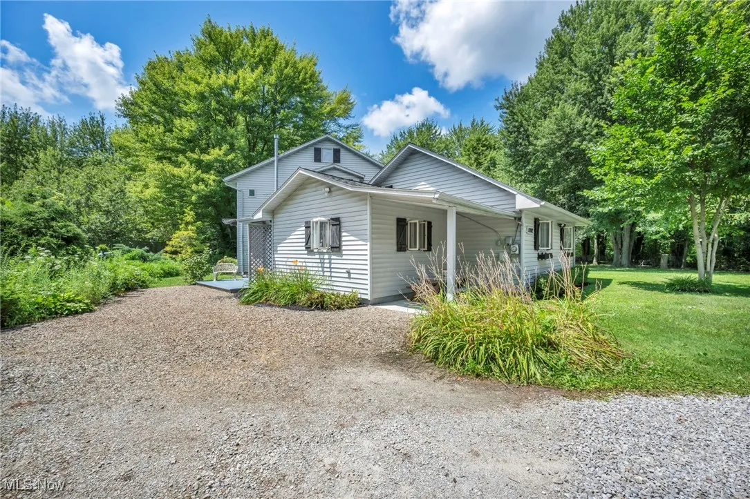 View of property exterior with a lawn and gravel driveway