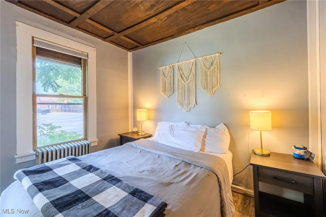 Bedroom with radiator heating unit, wooden ceiling, and coffered ceiling