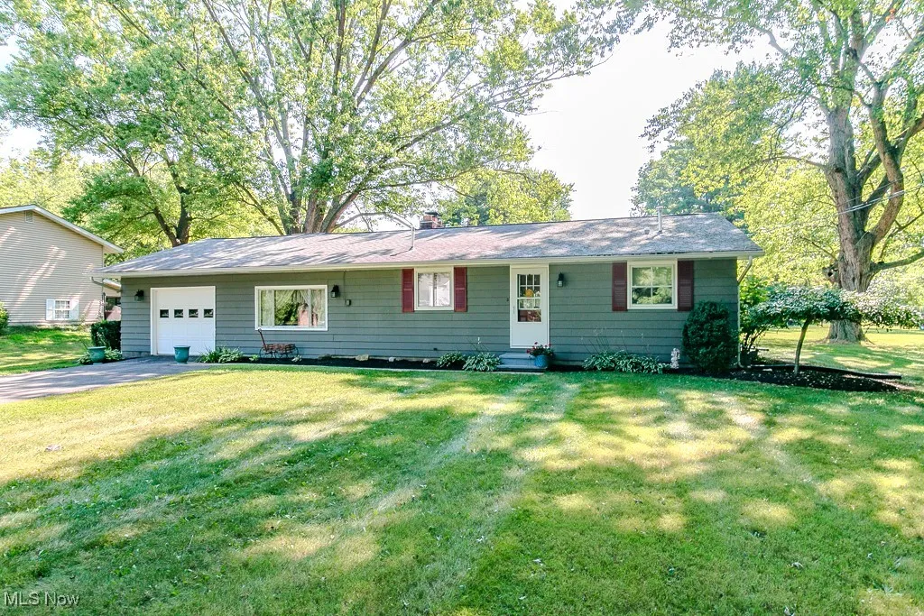 Ranch-style home with a garage, a front yard, a chimney, asphalt driveway, and entry steps