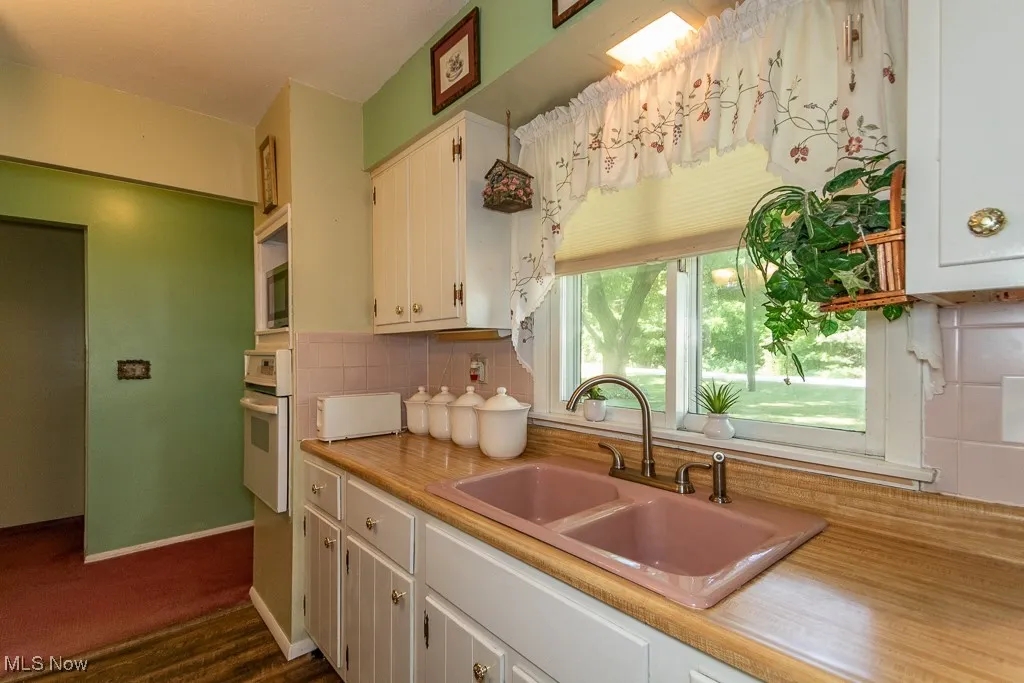 Kitchen featuring oven, light countertops, white cabinetry, and backsplash