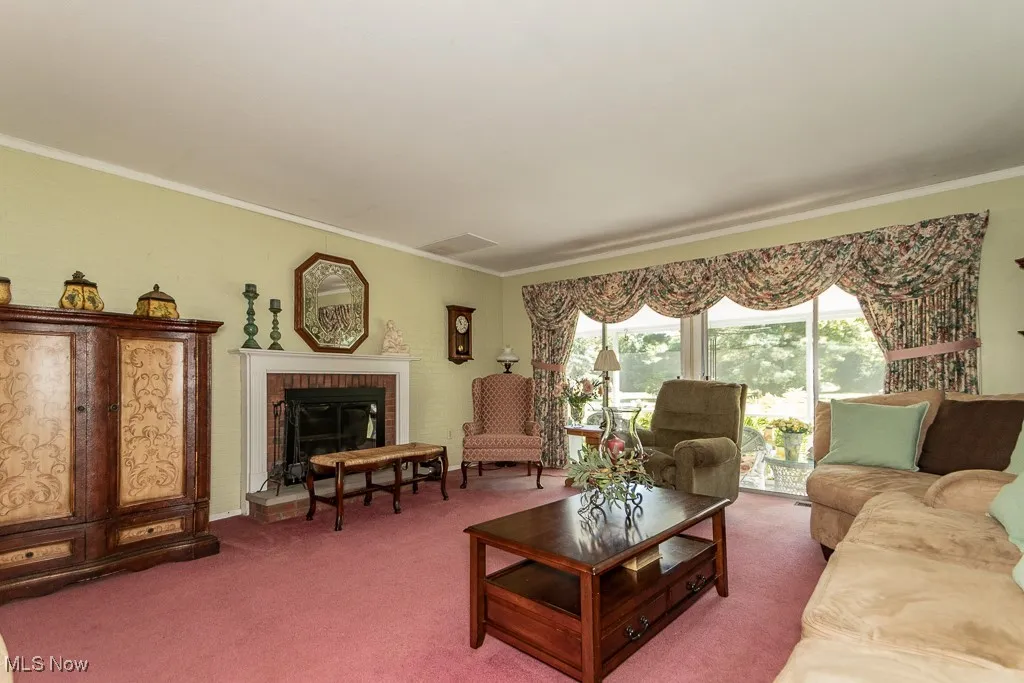 Living room featuring carpet, crown molding, and a fireplace