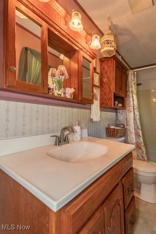 Bathroom featuring vanity, wallpapered walls, and a shower with curtain