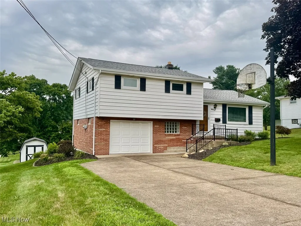 Split level home with brick siding, a shed, and a front lawn