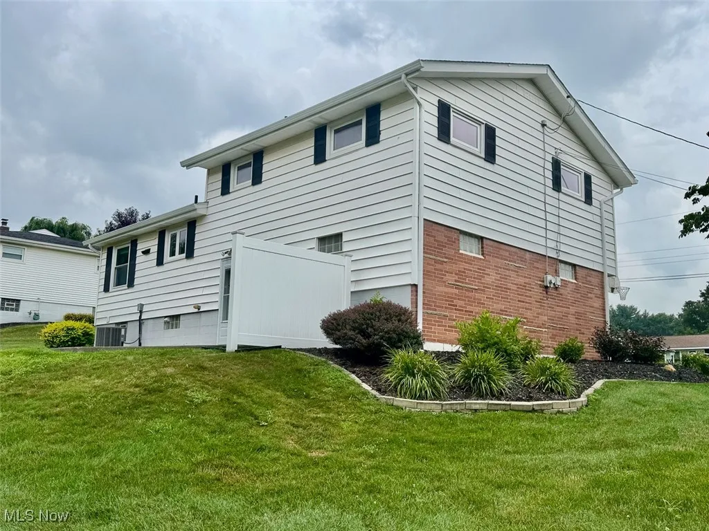 View of property exterior with a yard and brick siding