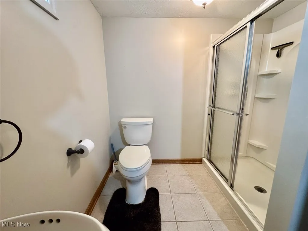 Full bath with a shower stall, tile patterned flooring, and a textured ceiling