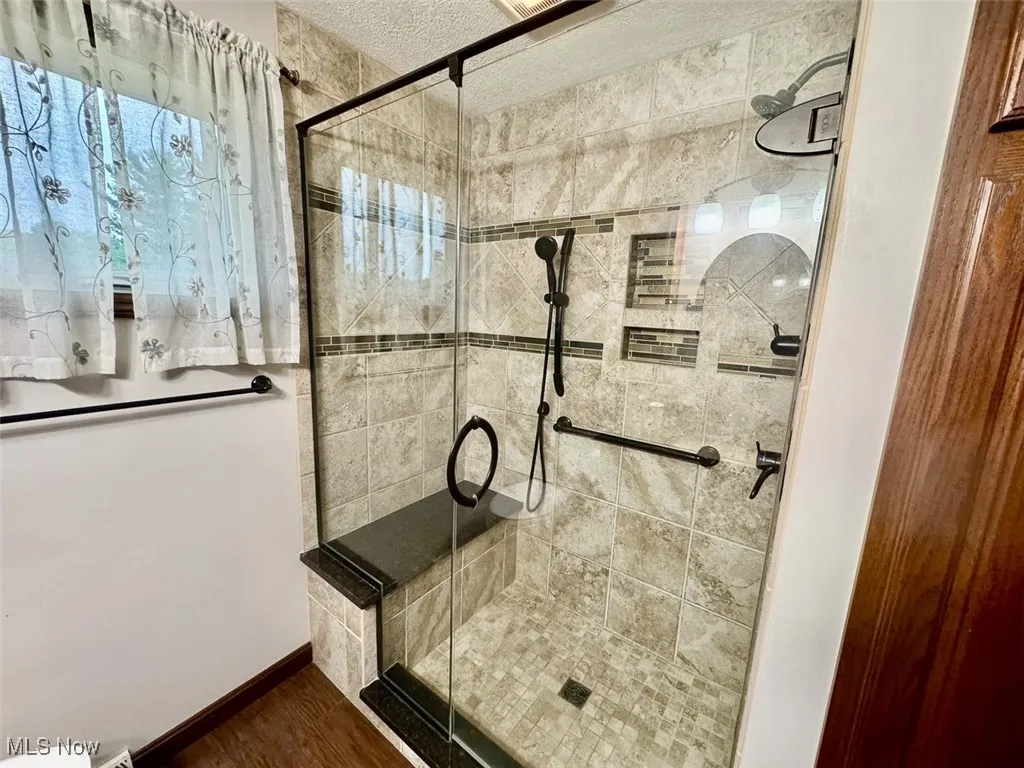 Bathroom with a stall shower, wood finished floors, and a textured ceiling