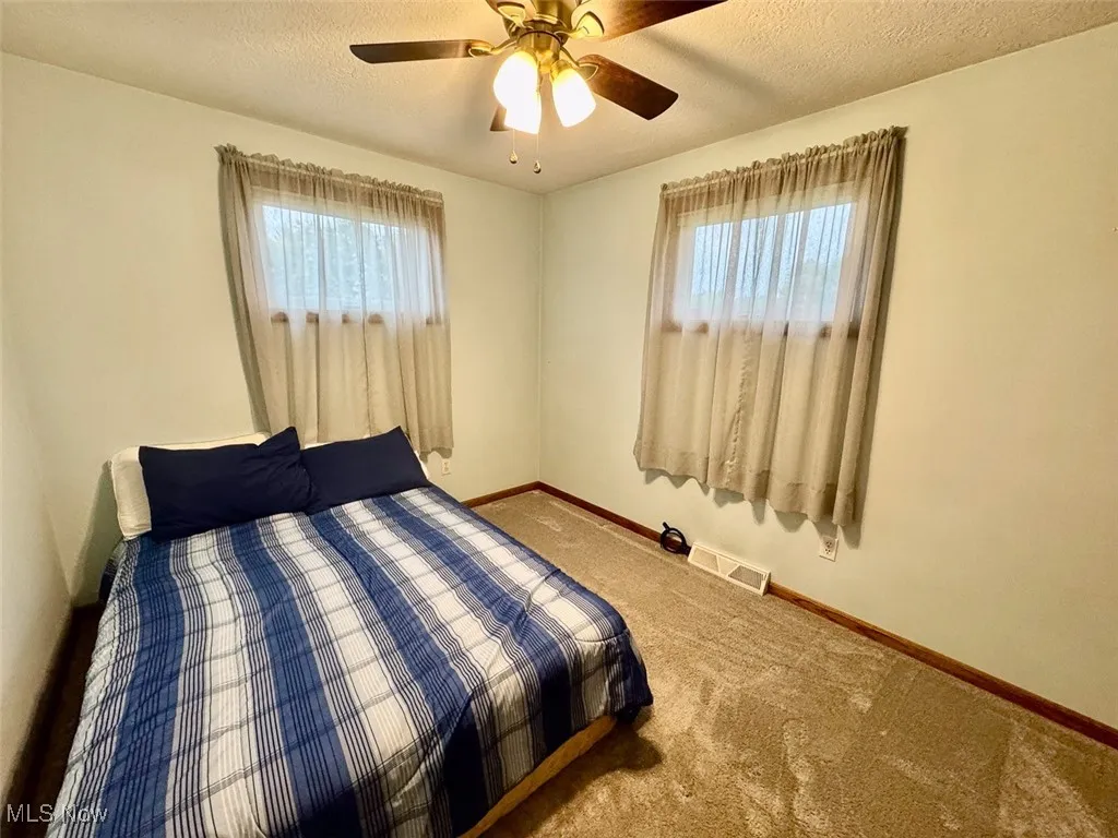 Carpeted bedroom featuring a textured ceiling and ceiling fan