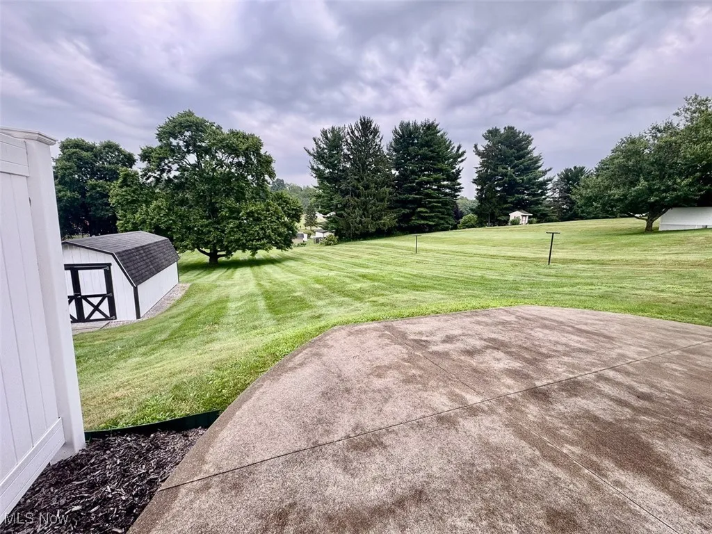 View of grassy yard featuring a shed and a patio