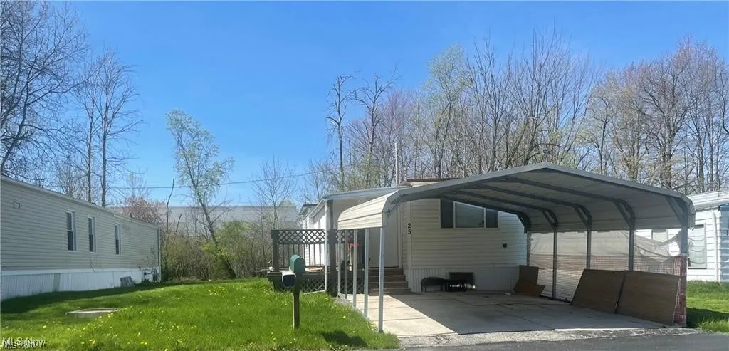 View of parking with a detached carport and driveway