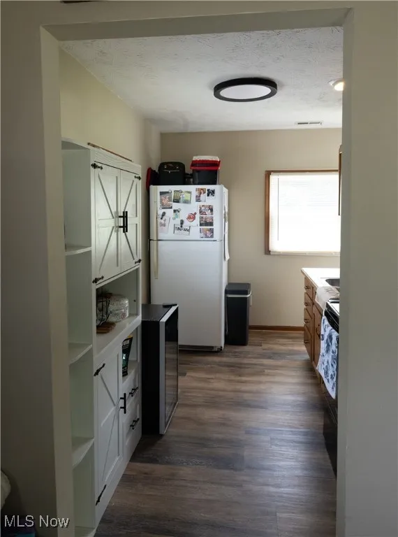 Kitchen with a textured ceiling, freestanding refrigerator, dark wood-style flooring, open shelves, and wine cooler