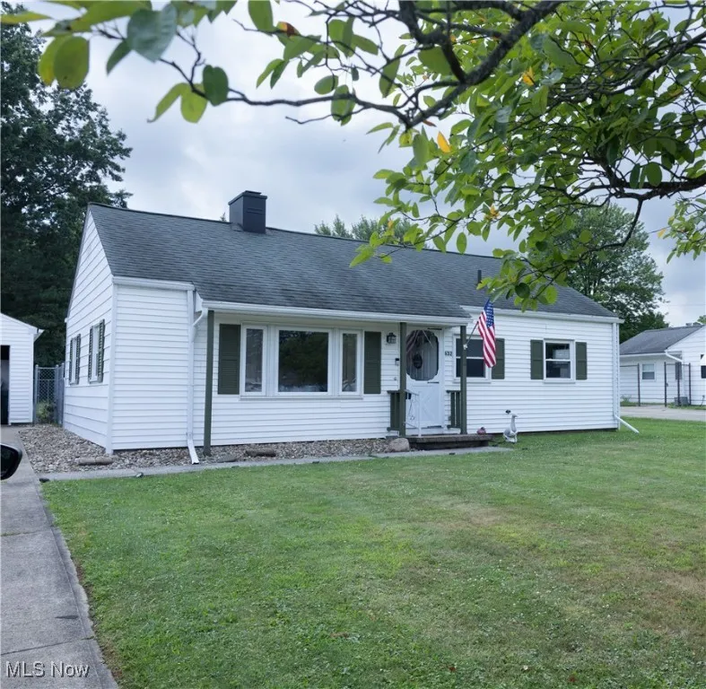 View of front of home featuring roof with shingles, a chimney, and a front yard