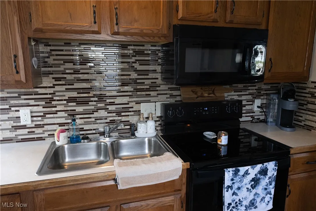 Kitchen with decorative backsplash, black appliances, light countertops, and brown cabinets