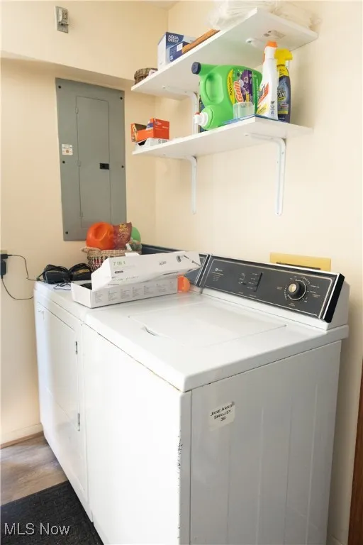Laundry room featuring washing machine and clothes dryer, electric panel, and light wood finished floors