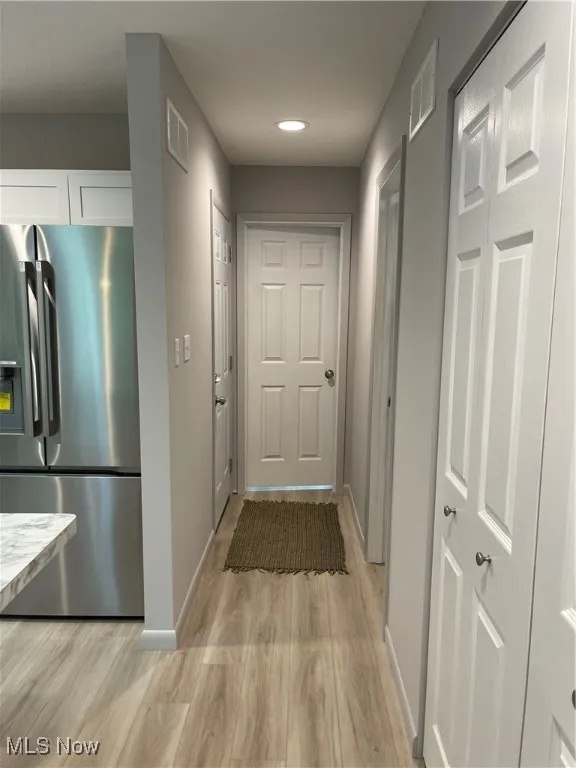 Corridor with light wood-style flooring and recessed lighting