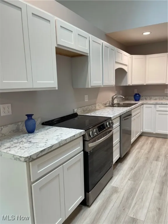 Kitchen featuring stove, light wood-style flooring, white cabinetry, recessed lighting, and dishwashing machine