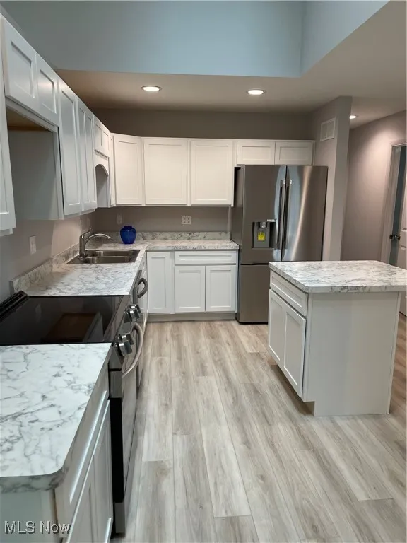 Kitchen with range, fridge, recessed lighting, a center island, and light wood finished floors