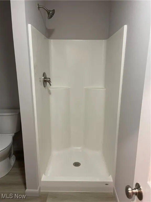 Full bath with a shower and wood finished floors