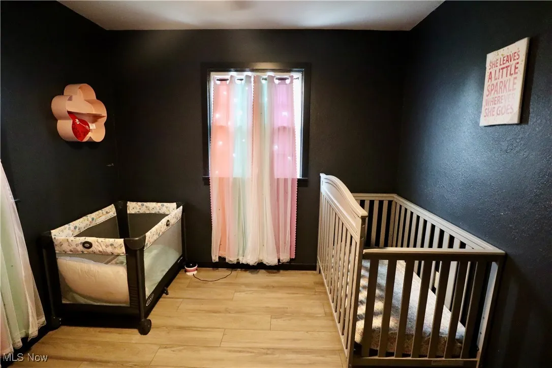 Bedroom with wood finished floors and a crib