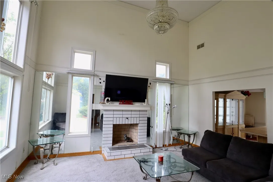 Living area with a towering ceiling, plenty of natural light, and a brick fireplace