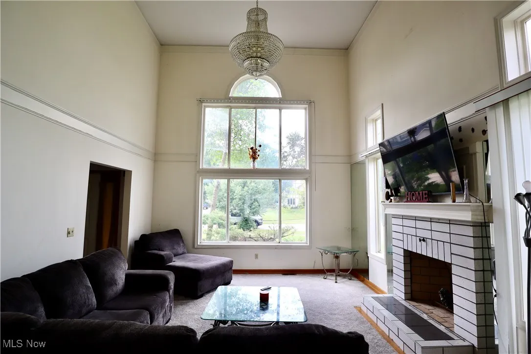 Living room with a high ceiling, carpet flooring, and a fireplace
