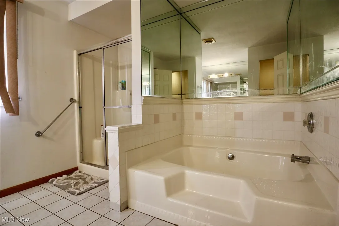 Full bath featuring a shower stall, a bath, and tile patterned flooring