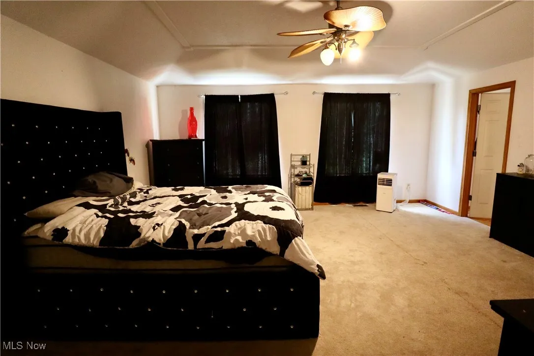 Carpeted bedroom featuring ceiling fan and baseboards