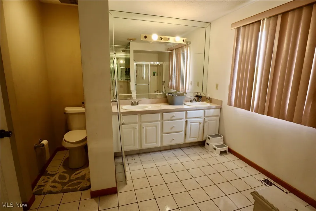 Full bath with tile patterned floors, double vanity, and a shower stall