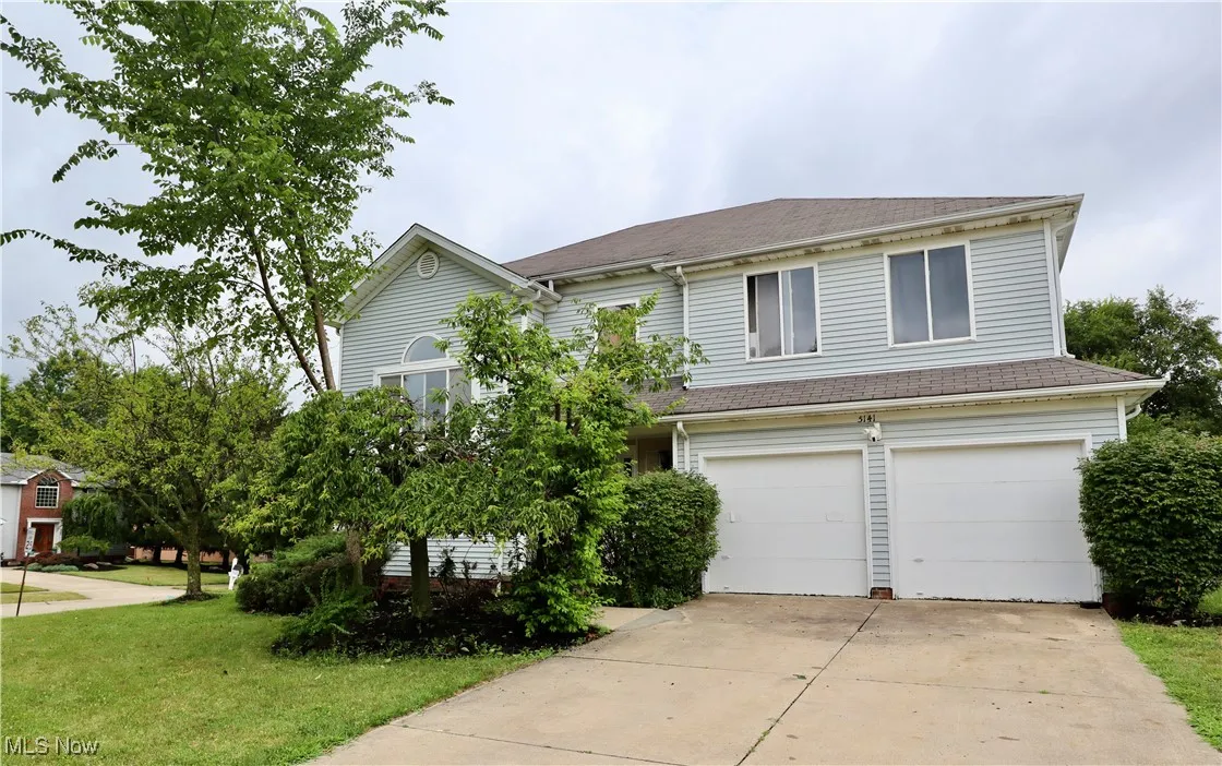 View of front of home with an attached garage, driveway, and a front lawn