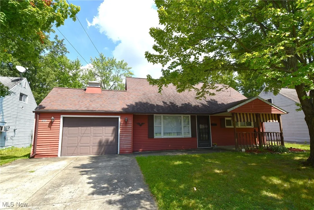 View of front facade with driveway, a front yard, an attached garage, and roof with shingles