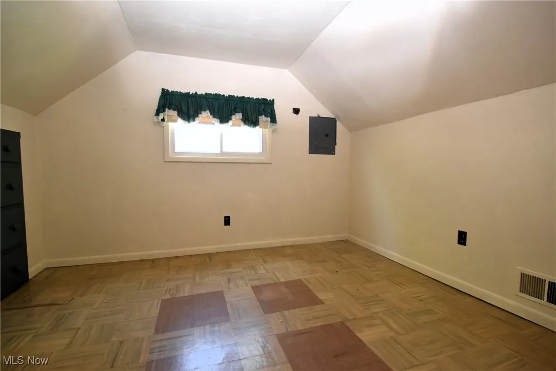 Additional living space featuring vaulted ceiling and electric panel