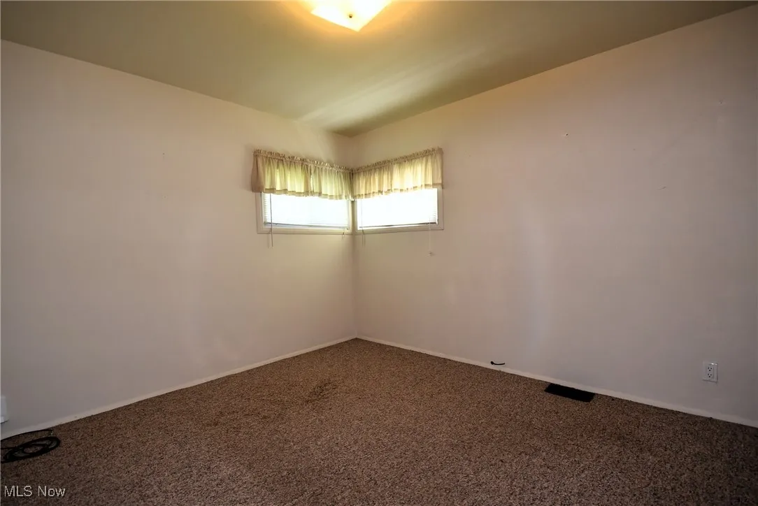 Spare room featuring carpet flooring and baseboards