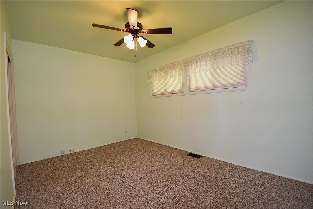 Carpeted empty room featuring ceiling fan and baseboards