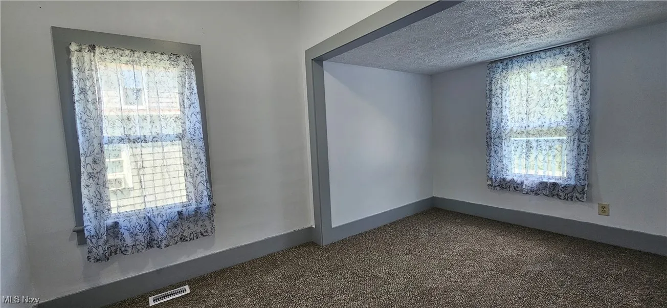 First bedroom with a textured ceiling and new carpet flooring