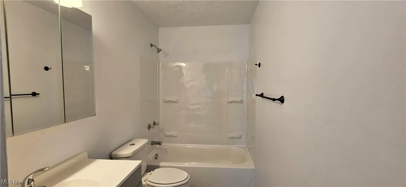 Full bath featuring a textured ceiling, tub / shower combination, toilet and vanity