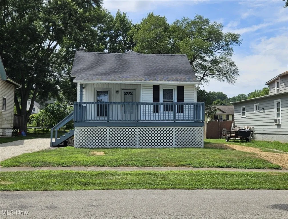 Bungalow-style home with partially covered porch, a front yard, a shingled roof, and stairs