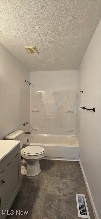 Bathroom with vanity, tub / shower combination, and a textured ceiling