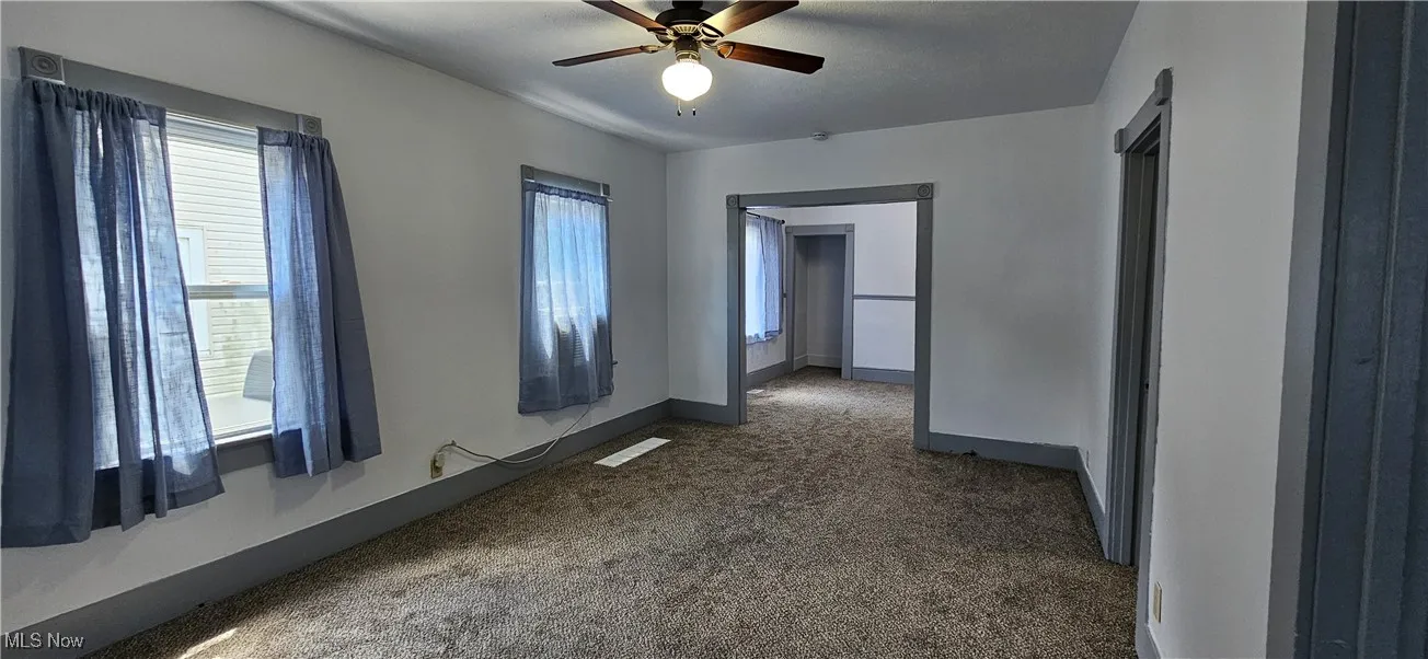 Carpeted living room featuring plenty of natural light and a ceiling fan