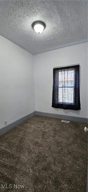 Second bedroom featuring high textured ceiling and new carpet floors