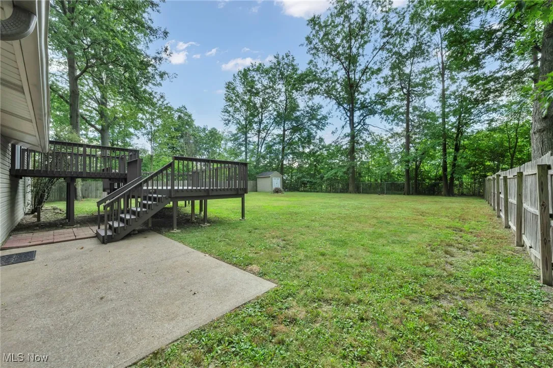 Fenced backyard with stairway, a patio area, a storage shed, and a wooden deck