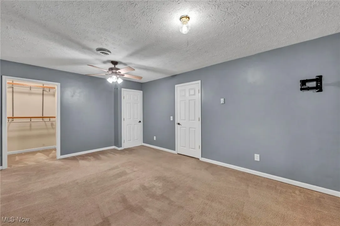 Unfurnished bedroom with carpet, a textured ceiling, and a ceiling fan