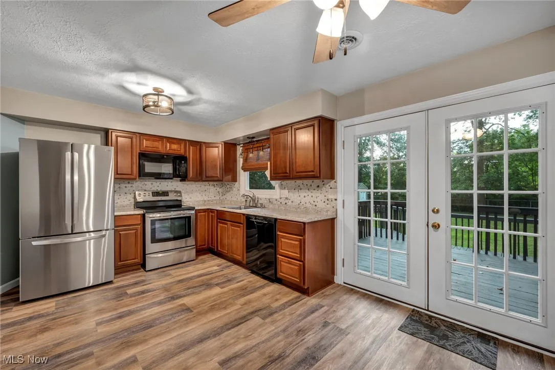 Kitchen with black appliances, french doors, tasteful backsplash, a textured ceiling, and brown cabinetry