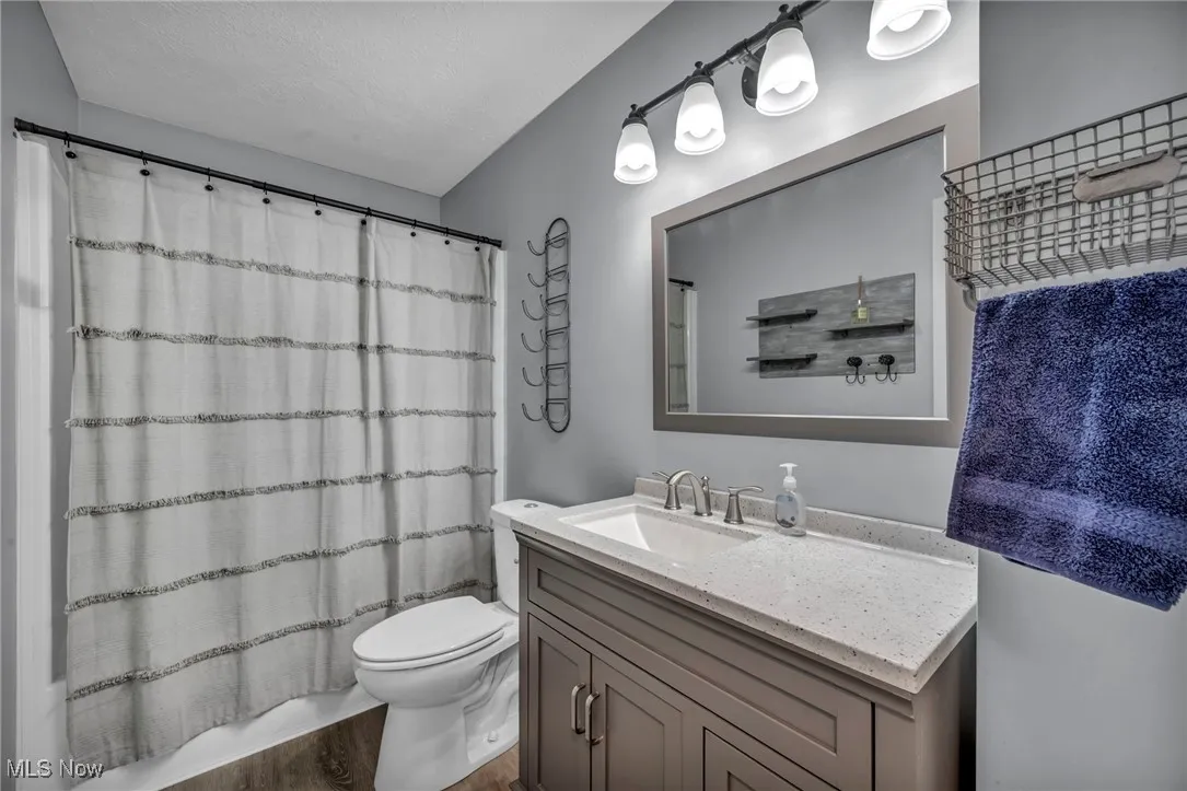 Full bath featuring vanity, wood finished floors, and a textured ceiling
